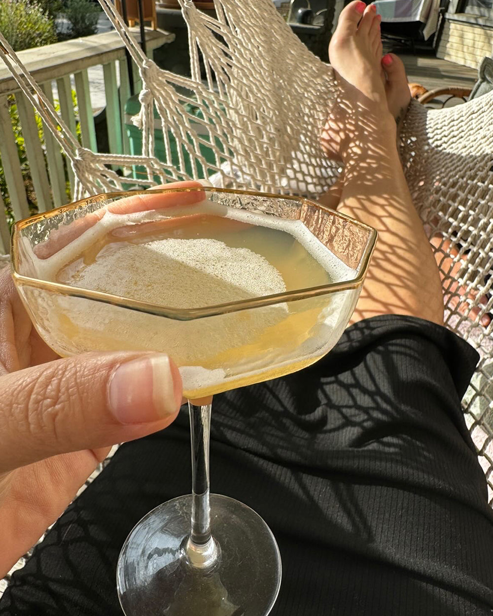 Person in hammock holding a non-alcoholic cocktail.