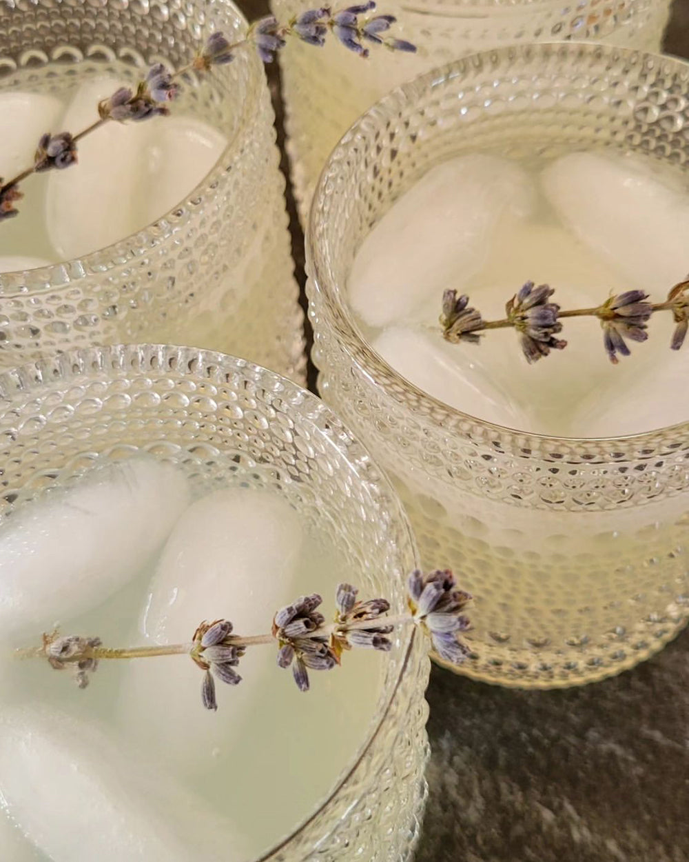 Three non-alcoholic cocktails in ornate glasses with lavender garnish.