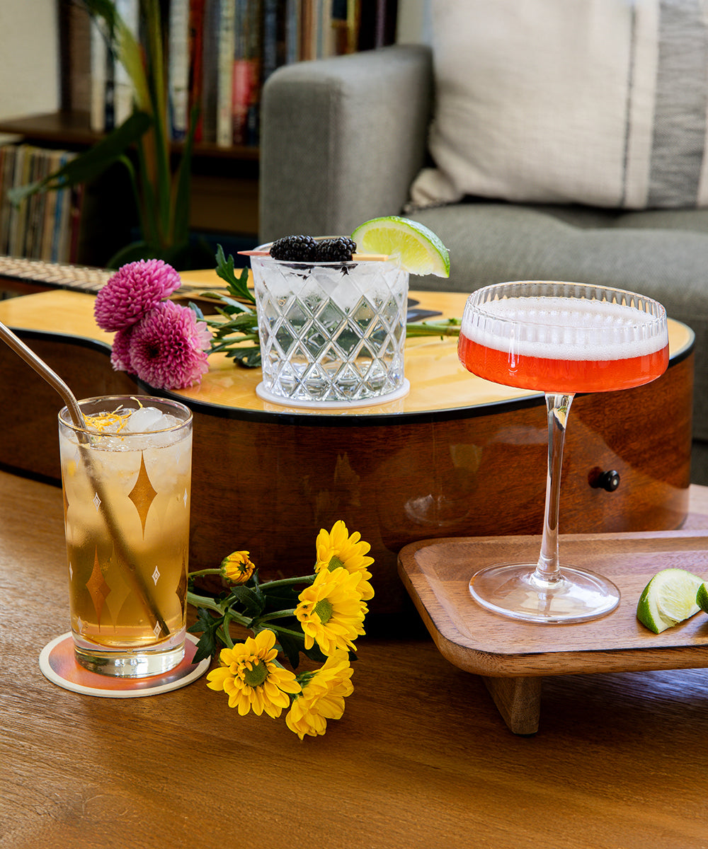 Zero-Proof Gin cocktails and guitar on wooden table in a living room.