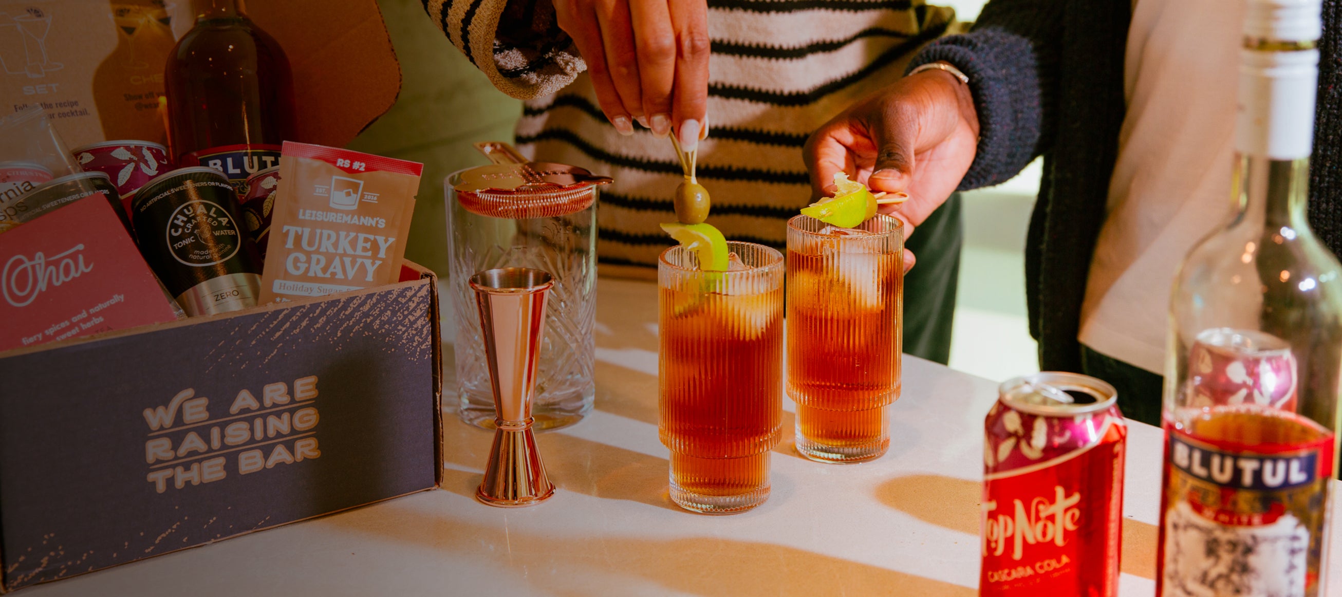 Woman in striped shirt adding olive garnish to non-alcoholic drinks. 