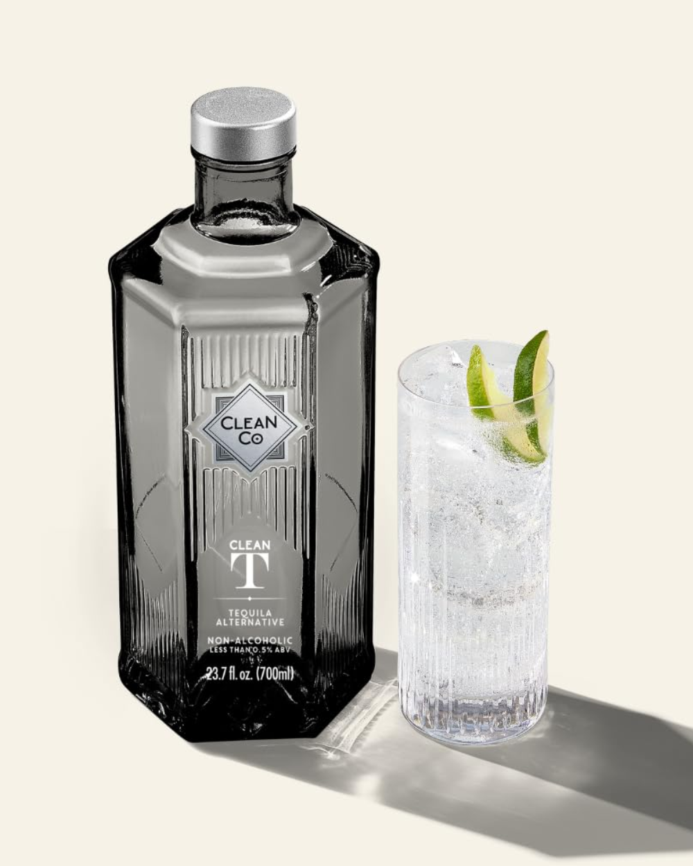 Clean Co tequila bottle with a cocktail garnished with lime on a light background