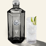 Clean Co tequila bottle with a cocktail garnished with lime on a light background