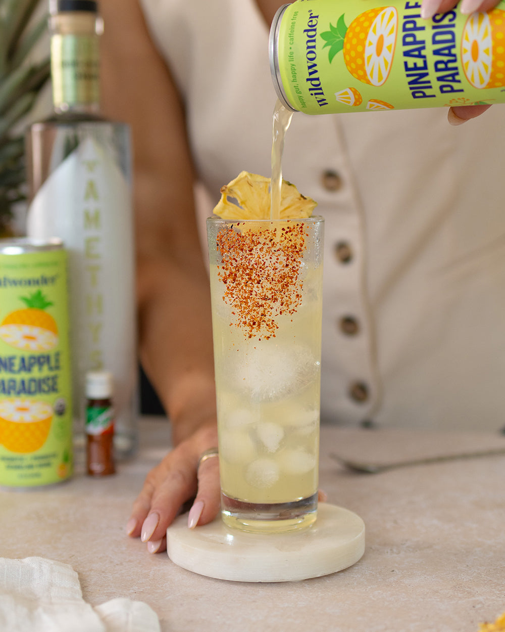 Woman pouring WildWonder Pineapple Paradise into zero-proof cocktail.