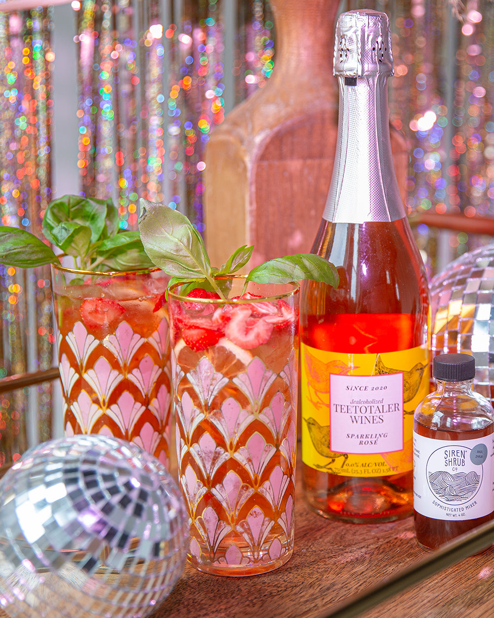 Various zero-proof cocktails on bar stand next to a disco ball.