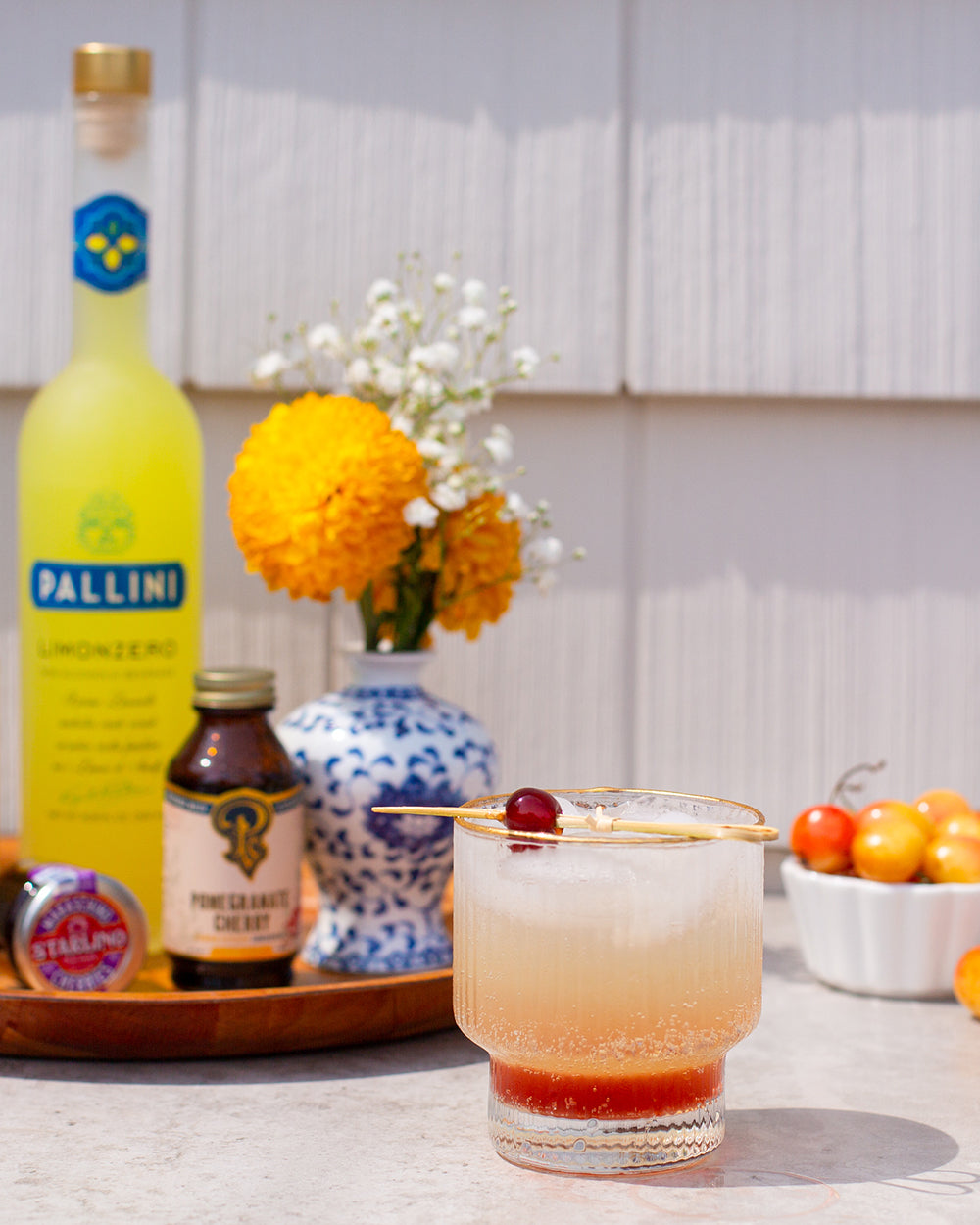  Amalfi Sunrise zero-proof cocktail on white surface with various products on tray in background.