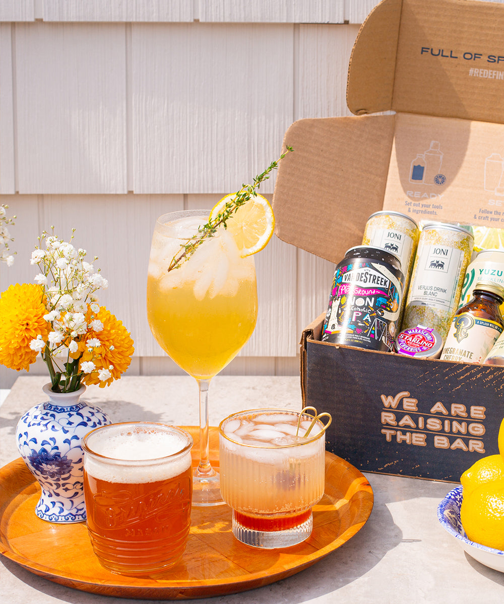 Pithy subscription box with non-alcoholic cocktails next to it on a wooden serving tray.