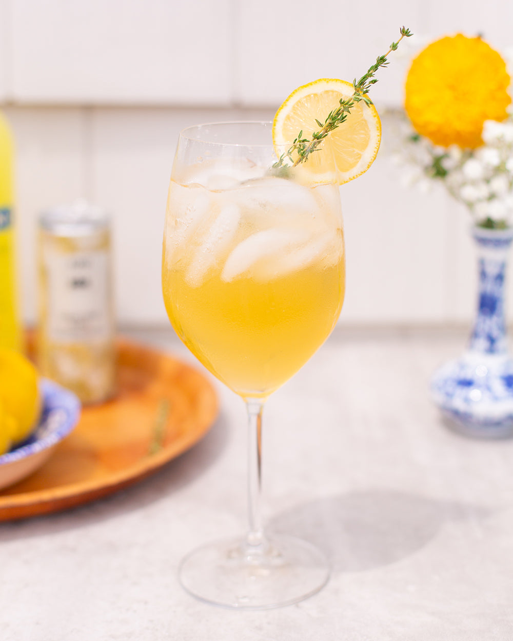 Limon Veritas zero-proof cocktail on white surface with various products on tray in background.