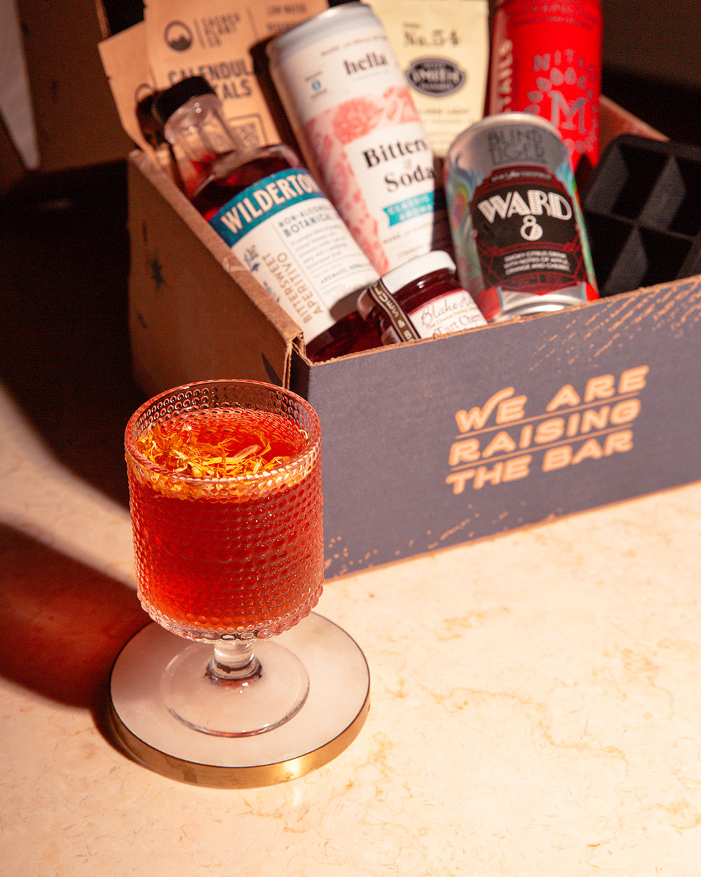 Afterglow zero-proof cocktail with subscription box in background.