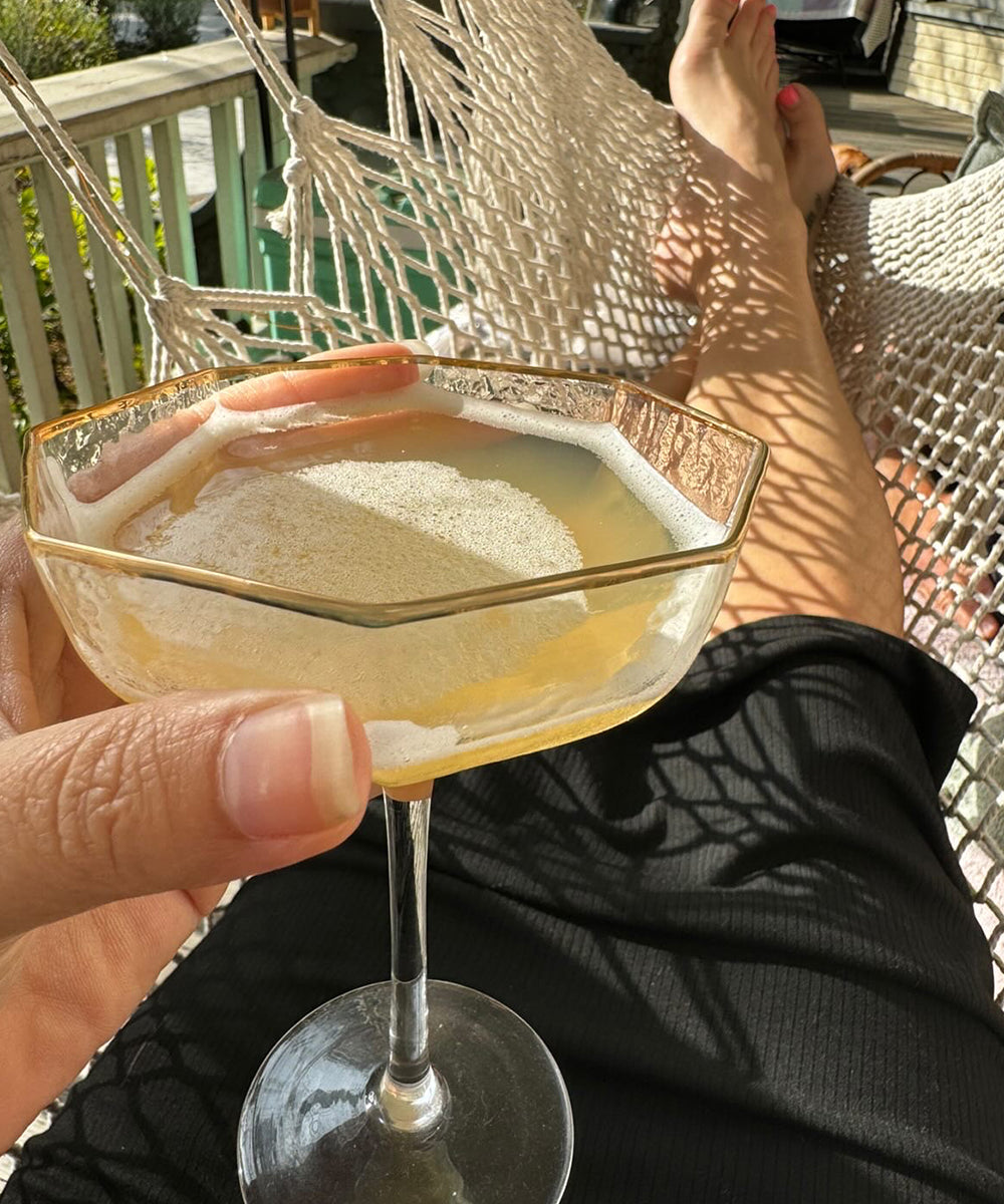 Person in hammock holding a non-alcoholic cocktail.