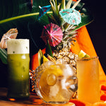Tropical cocktails with pineapple garnishes and colorful umbrellas on a wooden table.