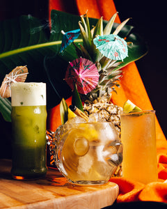 Tropical cocktails with pineapple garnishes and colorful umbrellas on a wooden table.