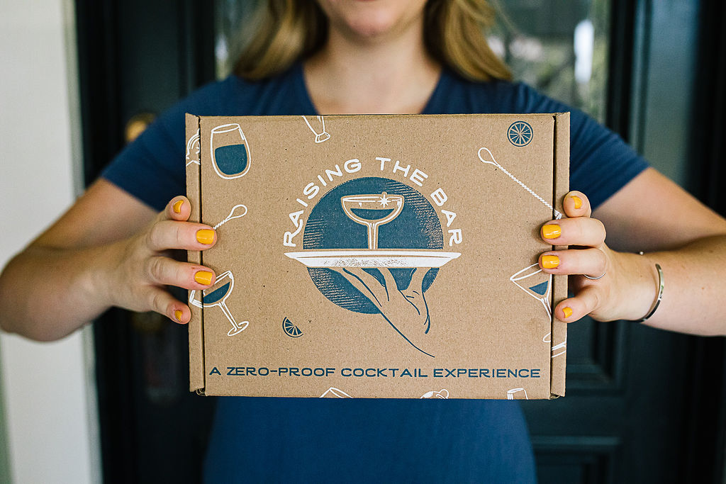 A woman holding up an alcohol-free subscription box.