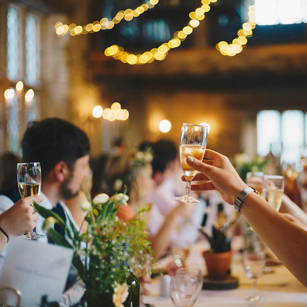 A joyful group of people toasting champagne at a wedding reception during happy hour.