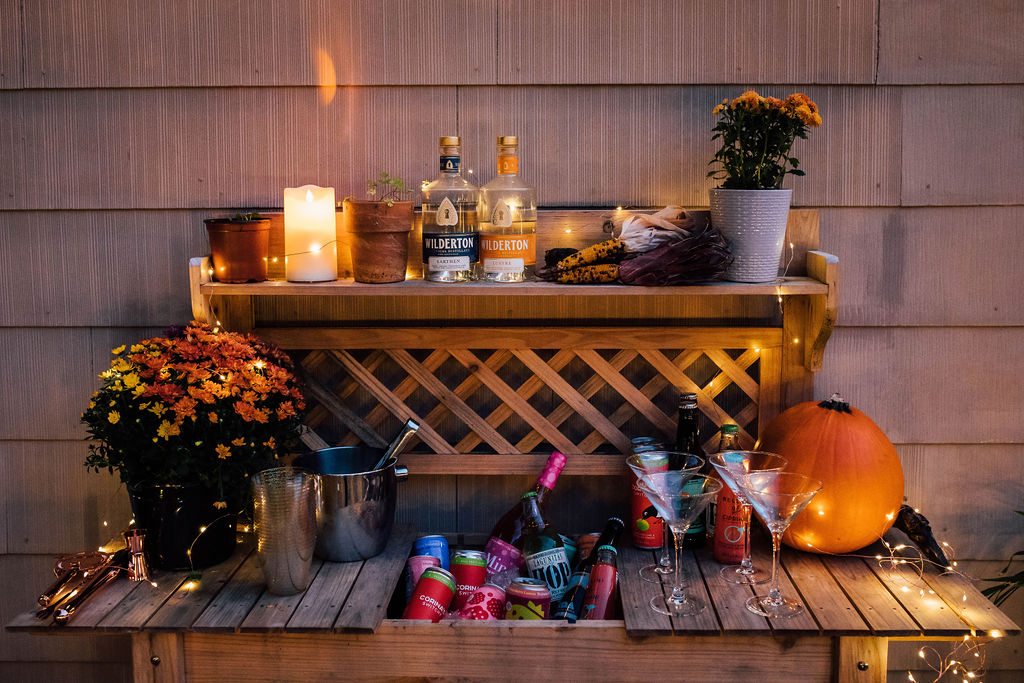 A wooden bar with candles and alcohol-free pumpkins on it.