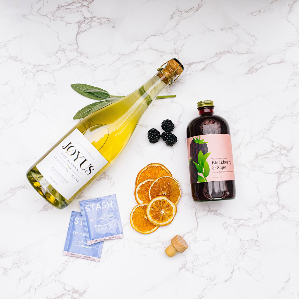 A subscription box featuring a cocktail-inspired bottle of wine and refreshing oranges elegantly displayed on a marble table.