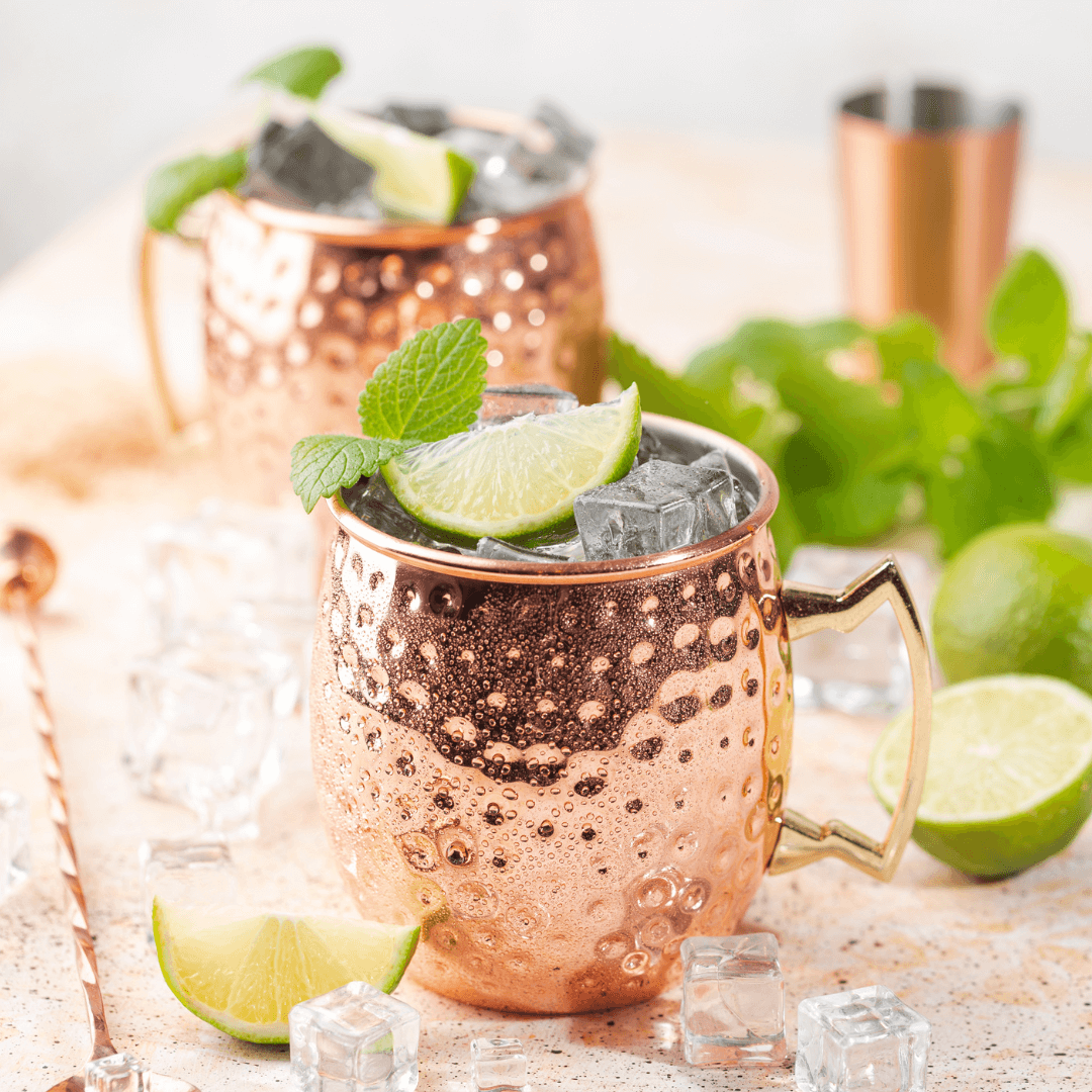 Two copper moscow mule mugs with lime and ice, perfect for a sober curious evening or happy hour at home.