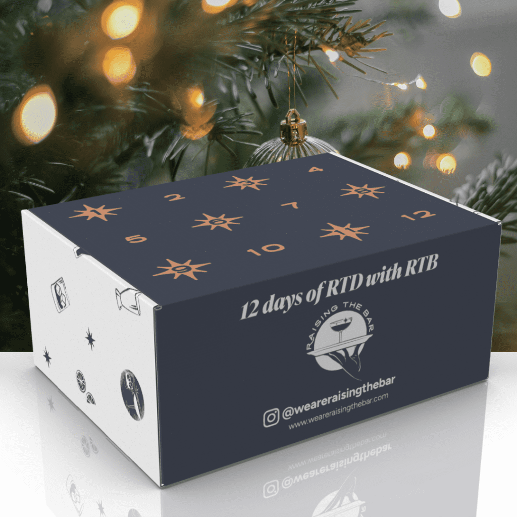 A christmas gift box with a christmas tree in the background.