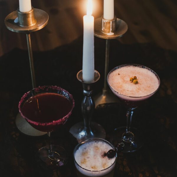 Three Charmed zero-proof cocktails with candles on a table at a happy hour event.